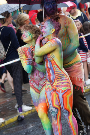 STOCKHOLM, SWEDEN - JUL 30, 2016: Colorful body painted girls smiling, a boy holding an umbrella in the Pride parade July 30, 2016 in Stockholm, Swedenのeditorial素材