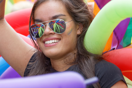 STOCKHOLM, SWEDEN - JUL 30, 2016: Beautiful smiling latin girl wearing sunglasses reflecting colorful balloons in the Pride parade in the Pride parade July 30, 2016 in Stockholm, Swedenのeditorial素材
