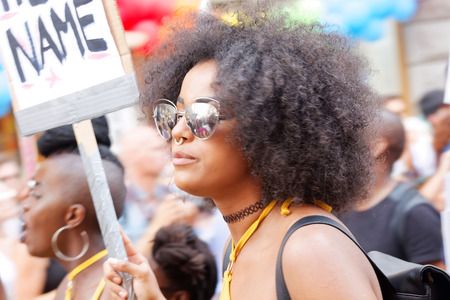 STOCKHOLM, SWEDEN - JUL 30, 2016: Woman with afro hair and sunglasses holding a sign in the Pride parade July 30, 2016 in Stockholm, Swedenのeditorial素材