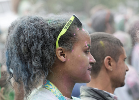 STOCKHOLM, SWEDEN - MAY 22, 2016: Young beautiful woman with sun glasses covered with color powder, side view in the air in the Color Run Event in Sweden, May 22, 2016のeditorial素材
