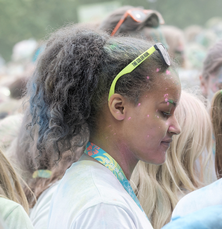 STOCKHOLM, SWEDEN - MAY 22, 2016: Young beautiful woman with sun glasses covered with color powder, side view in the air in the Color Run Event in Sweden, May 22, 2016のeditorial素材