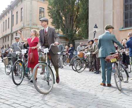 STOCKHOLM - SEPT 24, 2016: Young man and woman dressed in old fashioned tweed and red dress  with bicycle in the Bike in Tweed event September 24, 2016 in Stockholm, Swedenのeditorial素材
