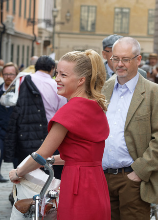 STOCKHOLM - SEPT 24, 2016: Smiling woman dressed in old fashioned red dress holding a bicycle the in the Bike in Tweed event September 24, 2016 in Stockholm, Swedenのeditorial素材