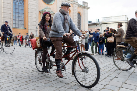 STOCKHOLM - SEPT 24, 2016: Man and woman dressed in old fashioned clothes cycling on a tandem bicycle in the Bike in tweed event September 24, 2016 in Stockholm, Swedenのeditorial素材