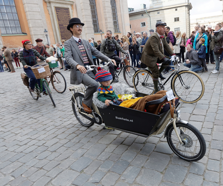 STOCKHOLM - SEPT 24, 2016: Cycling father transporing his child in a special bicycle, dressed in old fashioned clothes in the Bike in tweed event September 24, 2016 in Stockholm, Swedenのeditorial素材