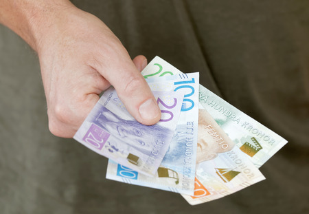 Hand holding swedish bank notes, dark green backgroundの写真素材
