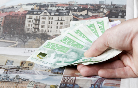 Hand holding swedish currency symbolising the expensive flats in the housing adの写真素材