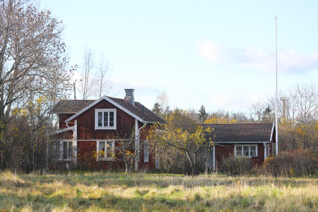 Red traditional cottages and white windows on a meadowの写真素材