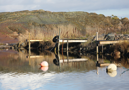 Three small wooden bridges and some buoys in the rural harbor. A cliff en the backgroundの写真素材