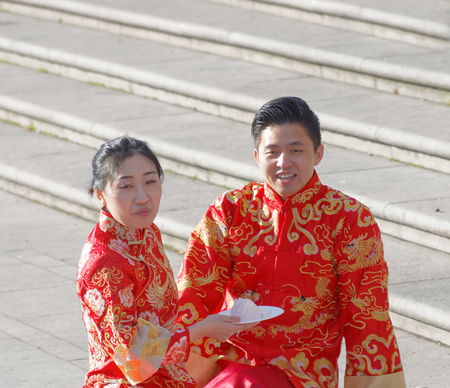 STOCKHOLM, SWEDEN - APRIL 23, 2016: Asian couple in traditional clothes eating breakfast in the public park Kungstradgarden in central Stockholmのeditorial素材