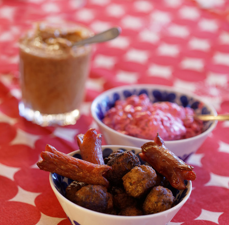 Home made meatballs, sausage, beetroot salad and mustard on the Christmas table with a red cloth
の写真素材