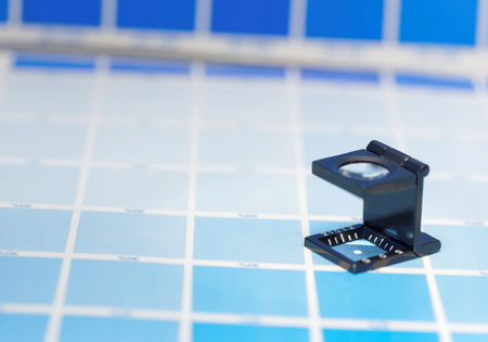 Magnifier or printer's loupe sits on a cyan test sheet in a pre-press workshopの写真素材