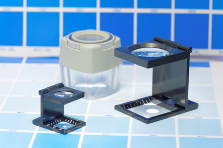 Three magnifier or printer's loupe sits on a cyan test sheet in a pre-press workshopの写真素材
