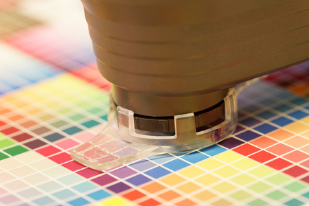 Closeup of spectrometer used for proofing on a leaf of the multi color test print in a pre-press workshopの写真素材