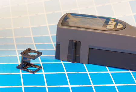 Scanning densitometer and a magnifyer on a leaf of the cyan test print in a pre-press workshop when proofingの写真素材