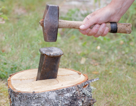Hand holding a sledgehammer, hit a wedge to split a birch logの写真素材