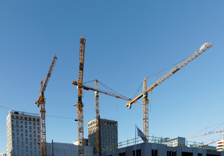 Sihouette of yellow cranes, blue sky and high buildings at Hagastaden in Stockholm, Swedenの写真素材
