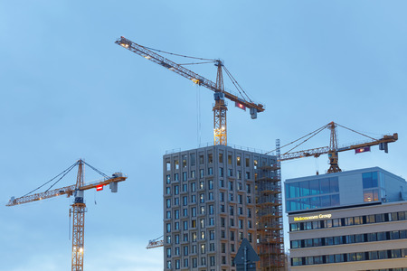 STOCKHOLM - JAN 15, 2017: Sihouette of yellow cranes, blue sky and high buildings. January 15, 2017...