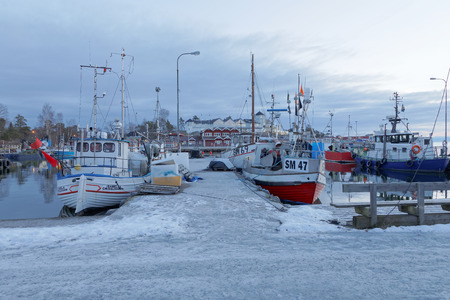 STOCKHOLM - JAN 31, 2017: Many fishing boats in the rural harbor in the morning sun. Red houses in the background. January 21, 2017 in Grisslehamn, Swedenのeditorial素材