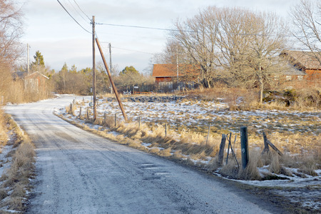 Rural contry road covered with snow and ice and red houses in warm morning light during winterの写真素材