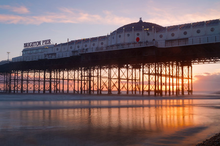 Brighton pier at sunset, warm red and orange colors. The pier reflecting in the waterのeditorial素材