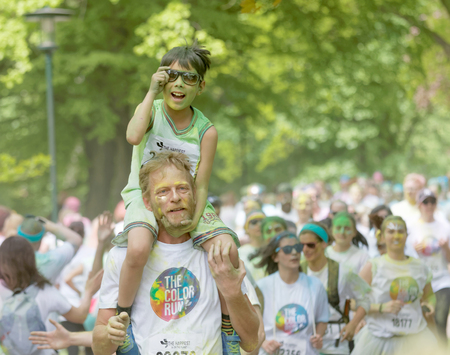 STOCKHOLM, SWEDEN - MAY 22, 2016: Young boy with green paint in his face on his fathers shoulders in...