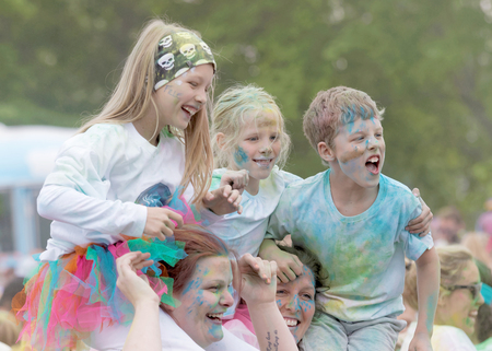 STOCKHOLM, SWEDEN - MAY 22, 2016: Smiling young children covered with blue paint teir parents...