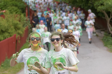 STOCKHOLM, SWEDEN - MAY 22, 2016: Group of running, happy, smiling teenagers covered with colorful...