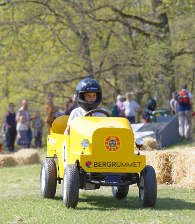 STOCKHOLM, SWEDEN - MAY 21, 2017: Boy driving a home made soapbox car downhill on a field, people in the background in the race Gardesloppet at Djurgarden, Stockholm, Sweden. May 21, 2017のeditorial素材