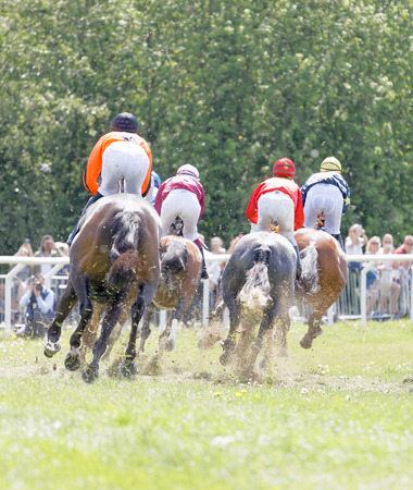 STOCKHOLM, SWEDEN - JUNE 06, 2017: Rear view of colorful jockeys on race horses riding in a curve at Nationaldags Galoppen at Gardet. June 6, 2017 in Stockholm, Swedenのeditorial素材