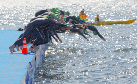 STOCKHOLM - AUG 26, 2017: The female swimming competitors wearing black swimsuits jump into the water after the start signal in the Women's ITU World Triathlon series event August 22, 2017 in Stockholm, Swedenのeditorial素材