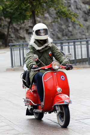 STOCKHOLM, SWEDEN - SEPT 02, 2017: Woman in parka jacket driving a red vespa scooter at the Saint Eriks bridge, Stockholm, Sweden, September 02, 2017のeditorial素材