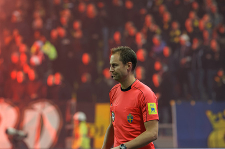 SOLNA SWEDEN - OCT 30, 2017: Football referee in red shirt, audience in the background. October 30 2017,Solna,Swedenのeditorial素材