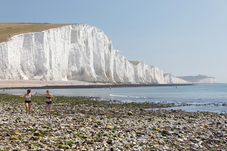 SUSSEX, GREAT BRITAIN: People sunbathing having the white chalk cliffs in the Seven Sisters Country Park in the background. in Sussex, Great Britainの写真素材