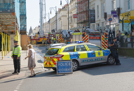 BRIGHTON, GREAT BRITAIN - JUN 17, 2017: Two police officers standing beside a police car stopping the traffic to help the fire brigade. June 17, 2017 in Brighton, Great Britainのeditorial素材