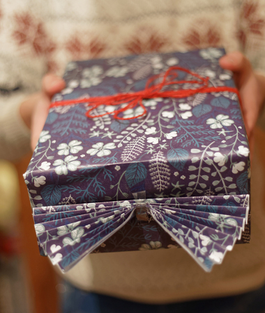 Man giving a Christmas present decorated with red ribbon. Short depth of focus