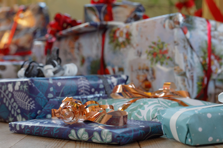 Pile of Christmas presents wrapped in colorful gift paper decorated with golden ribbon. Short depth...