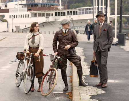 STOCKHOLM - SEPT 23, 2017: One woman and two men dressed in old fashioned clothes and holding bicycles from the 1960s in the Bike in Tweed event September 23, 2017 in Stockholm, Swedenのeditorial素材