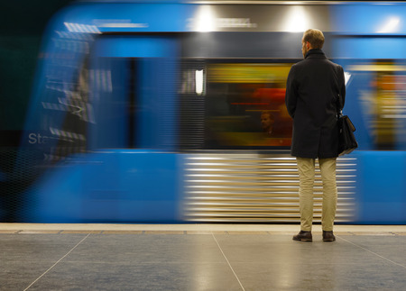 STOCKHOLM, SWEDEN - FEB 27, 2018: Rear view of man waiting for the subway train, his face reflecting in the window, on the platform in the underground Tekniska Hogskolan in Stockholm, Sweden, February 27, 2018のeditorial素材