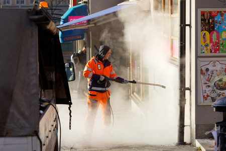 STOCKHOLM, SWEDEN - NOV 07, 2017: Official in orange uniform working to remove graffiti using steem on a wall in central Stockholm, Sweden, November 07, 2017のeditorial素材