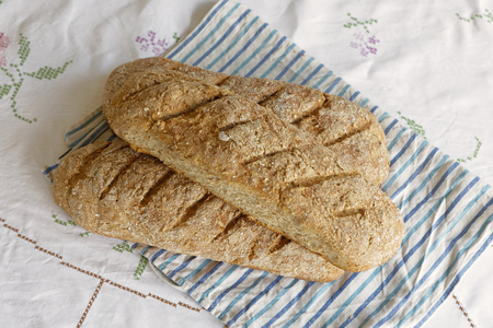 Homemade wheat and rye loaf bread on a blue and white striped kitchen towelの写真素材