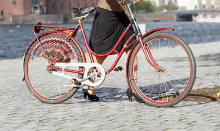 STOCKHOLM - SEPT 22, 2018: Woman leading red vintage bicycle ofer the cobble stone in the Bike in...
