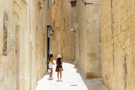 MDINA, MALTA - JUN 17 2018: People walking in a narrow alley in the medieval city Mdina on Malta. Mdina, Malta, June 17, 2018の写真素材