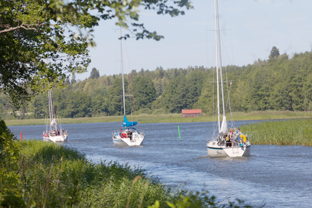 ALMSTA, SWEDEN - JUL 09 2018: Several sailships on a narrow canal Vaddo kanal through the forest. July 09, 2018, Almsta, Swedenの写真素材