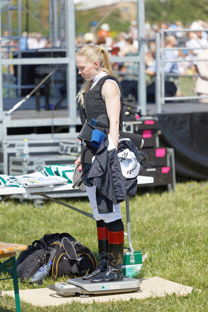 STOCKHOLM, SWEDEN - JUNE 06, 2019: Jockey Malin Holmberg weighing before the gallop horse race to adjust the extra weight in her vest at ATG Nationaldags Galoppen at Gardet. June 6, 2019 in Stockholm, Swedenのeditorial素材