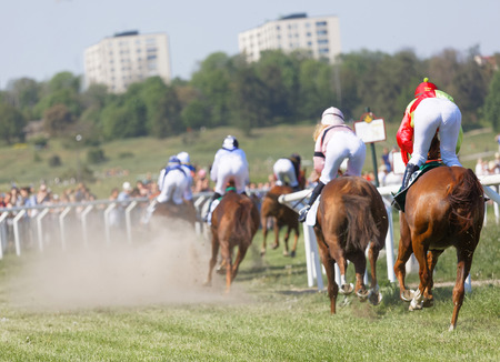STOCKHOLM, SWEDEN - JUNE 06, 2019: Rear view of standing colorful jockeys on race horses riding in a curve at Nationaldags Galoppen at Gardet. June 6, 2019 in Stockholm, Swedenのeditorial素材