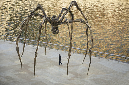 Woman walks under the giant spider of the artist Louise Bourgeois, outside theguggenheim museum of...
