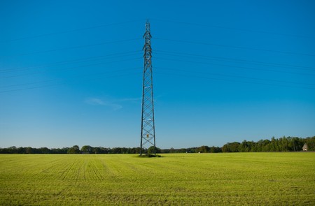 single electricity pylon in the middle of a grass fieldの写真素材