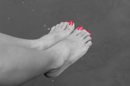 black and white pic of some tired feet above a canal after a long walk in Amsterdam. Only the nails are coloredの写真素材