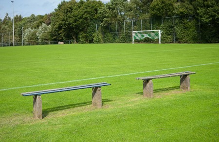 two empty benches along a soccerfieldの写真素材